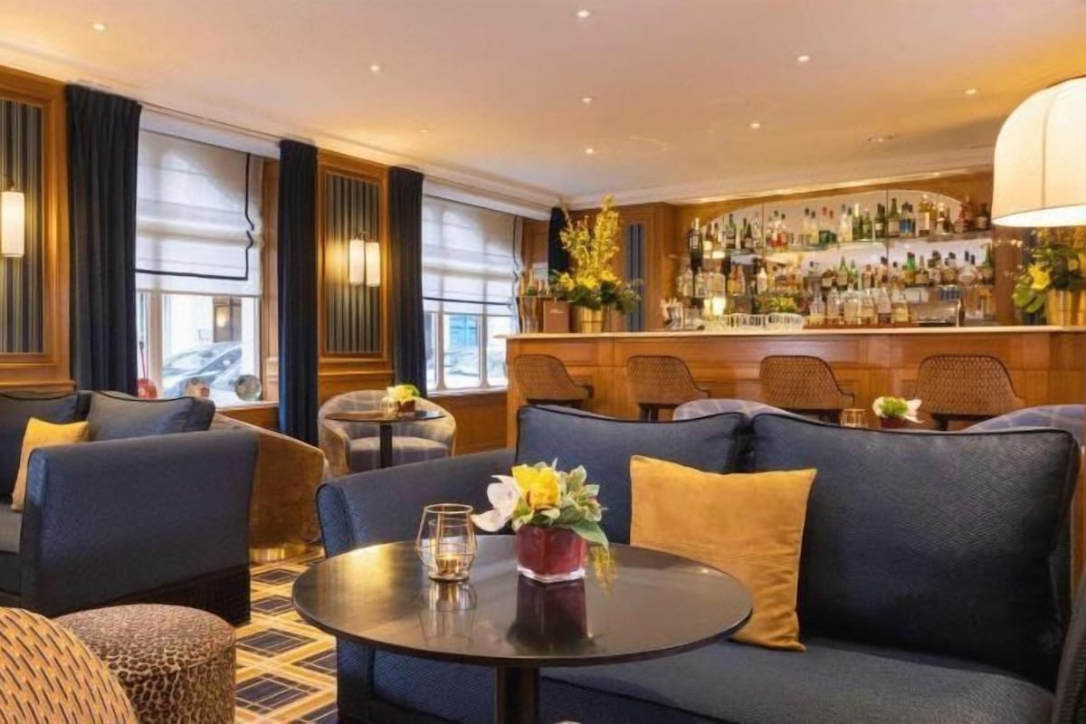 A hotel lobby with seating areas, a bar, and a view of the street.