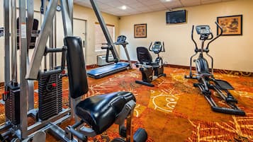 Un gimnasio con diversos equipos de ejercicio, incluyendo cintas de correr, bicicletas estáticas y máquinas de pesas.