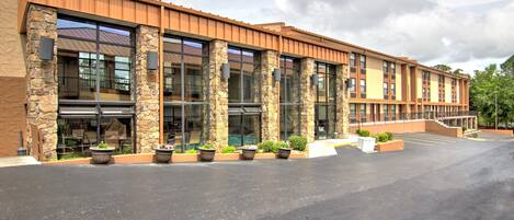 A modern building with stone columns, large windows, and a covered parking area.