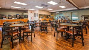 A restaurant with multiple tables and chairs, a buffet area, and a kitchen in the background.