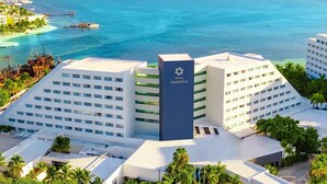 A hotel with a prominent tower, multiple buildings, and a view of the ocean. - Oasis Palm - All Inclusive (Cancun)