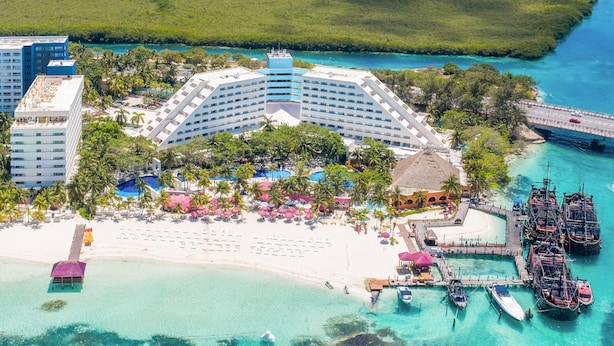 A resort with a large pool, beach area, and boats docked near the water. - Oasis Palm - All Inclusive (Cancun)