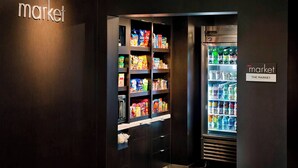 Een kamer in donkere kleuren, met een koelkast vol drankjes en een kastje met snacks en toiletartikelen.
