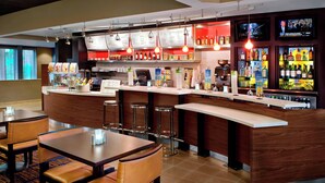 Een bar met een toonbank, barkrukken en een menukaart.