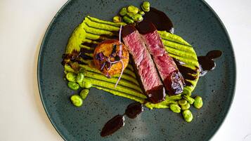 A plate with a steak, green sauce, and green vegetables.