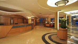 Eine geräumige Lobby mit einer geschwungenen Rezeption, einer großen Pflanze in einem Topf und einem modernen Deckenstil.