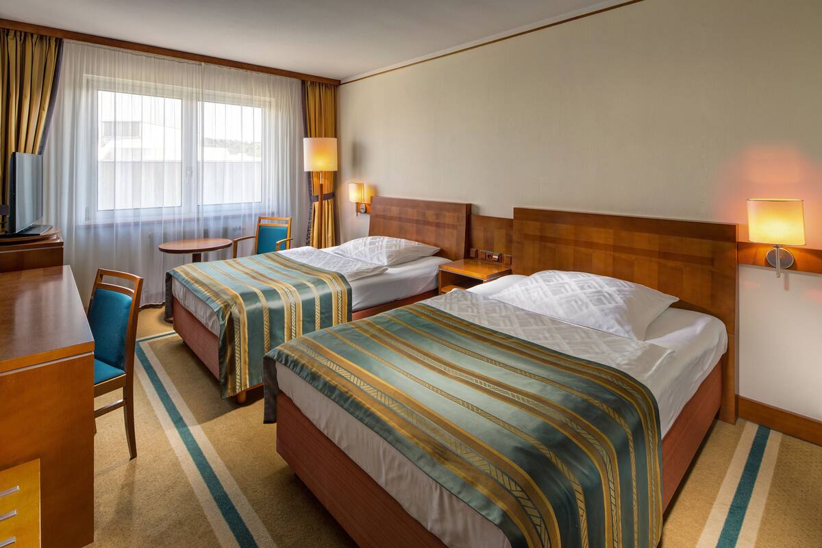 Une chambre d’hôtel avec deux lits, un bureau, une chaise et une petite table.