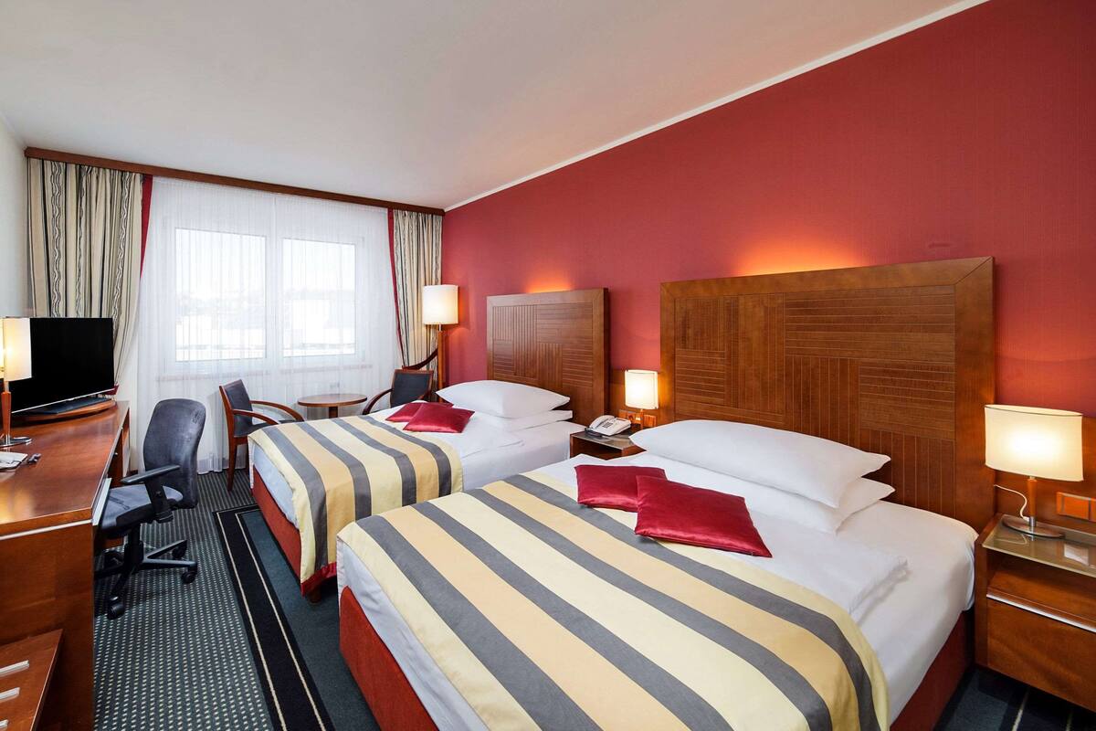 Une chambre d’hôtel avec deux lits, un bureau, une télévision et une chaise.