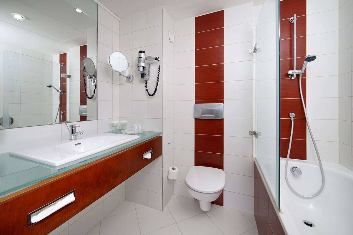 Une salle de bain moderne avec un lavabo en verre, des toilettes blanches et une douche.