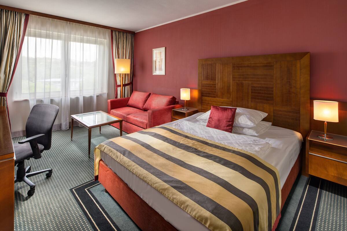 Une chambre d’hôtel avec un grand lit, un bureau, une chaise et un canapé.