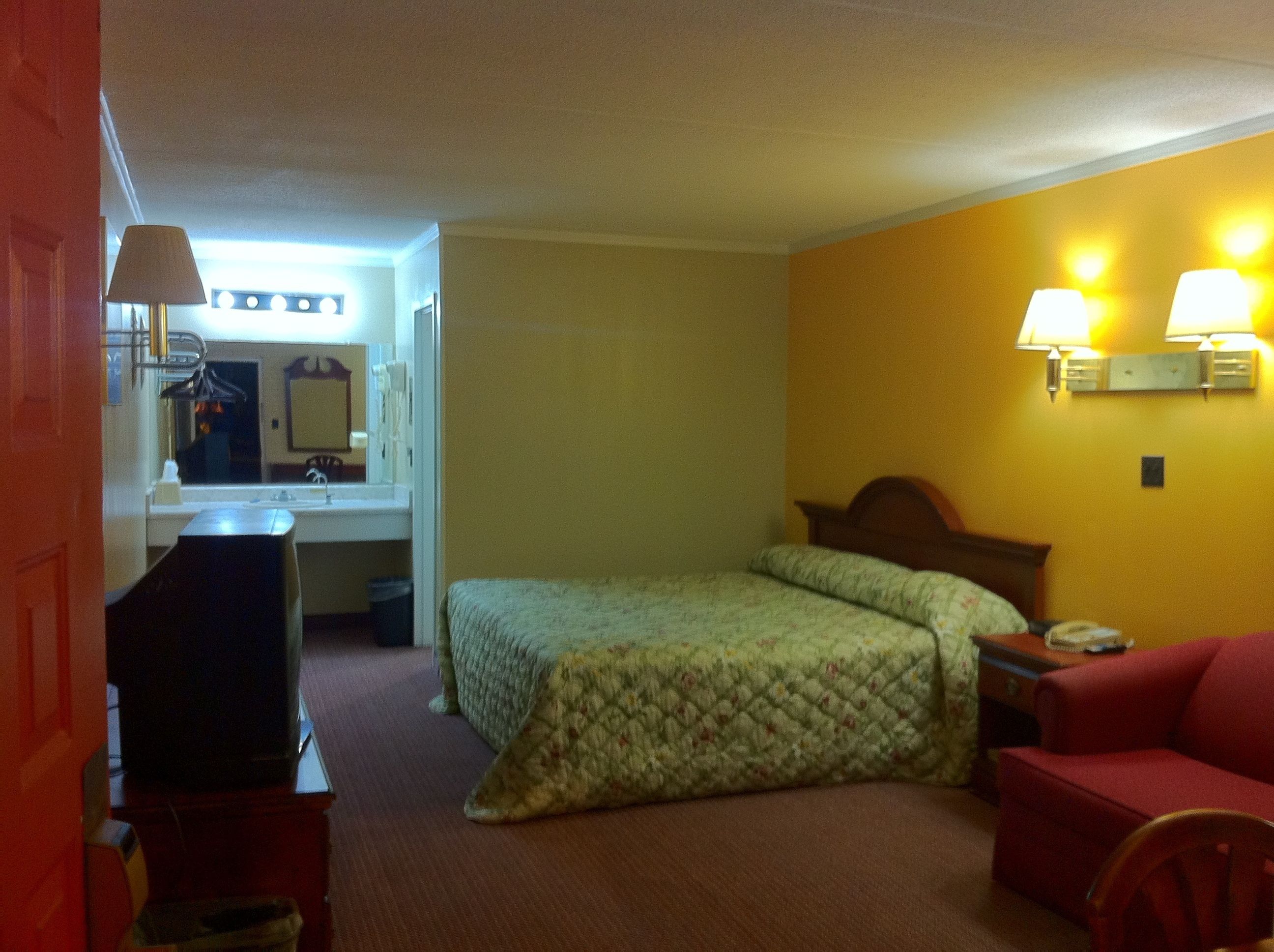 Een hotelkamer met een bed, een bureau, een stoel en een rode bank.