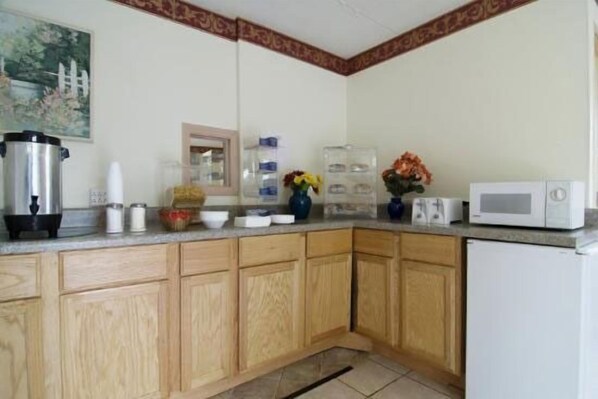 A kitchen with wooden cabinets, a microwave, a coffee maker, and a sink.