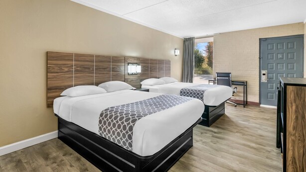 Une chambre d’hôtel avec deux lits, un bureau et une porte.