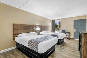 A hotel room with two beds, a desk, and a door.