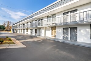 A modern motel with a row of single-story rooms, each with a balcony and a door marked with a number.