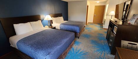 Habitación de hotel con dos camas, un escritorio, un espejo y una alfombra estampada.