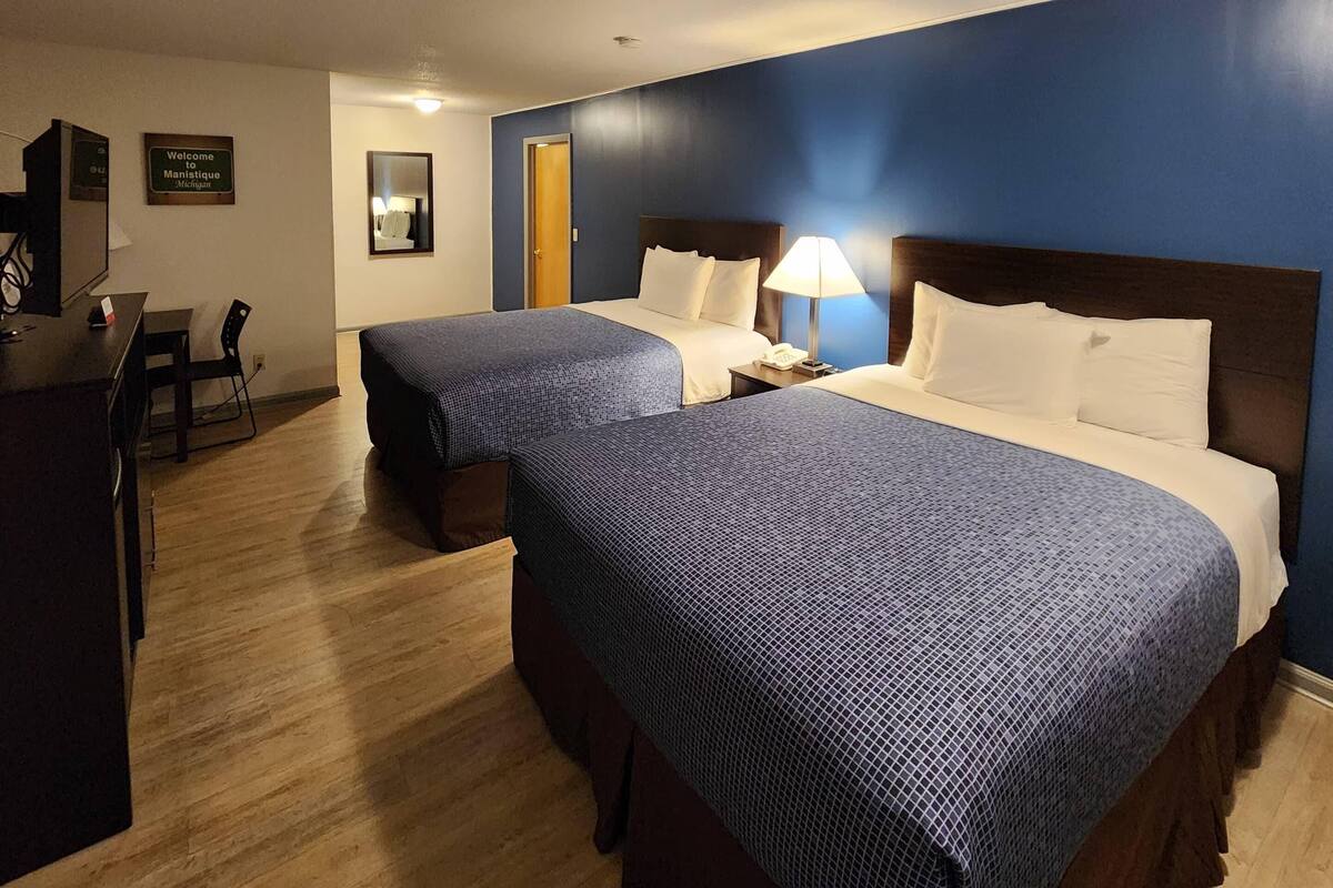 A hotel room with two beds, a desk, and a chair.