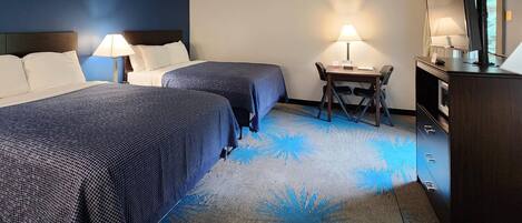A hotel room with two beds, a desk, a chair, a TV, and a dresser.