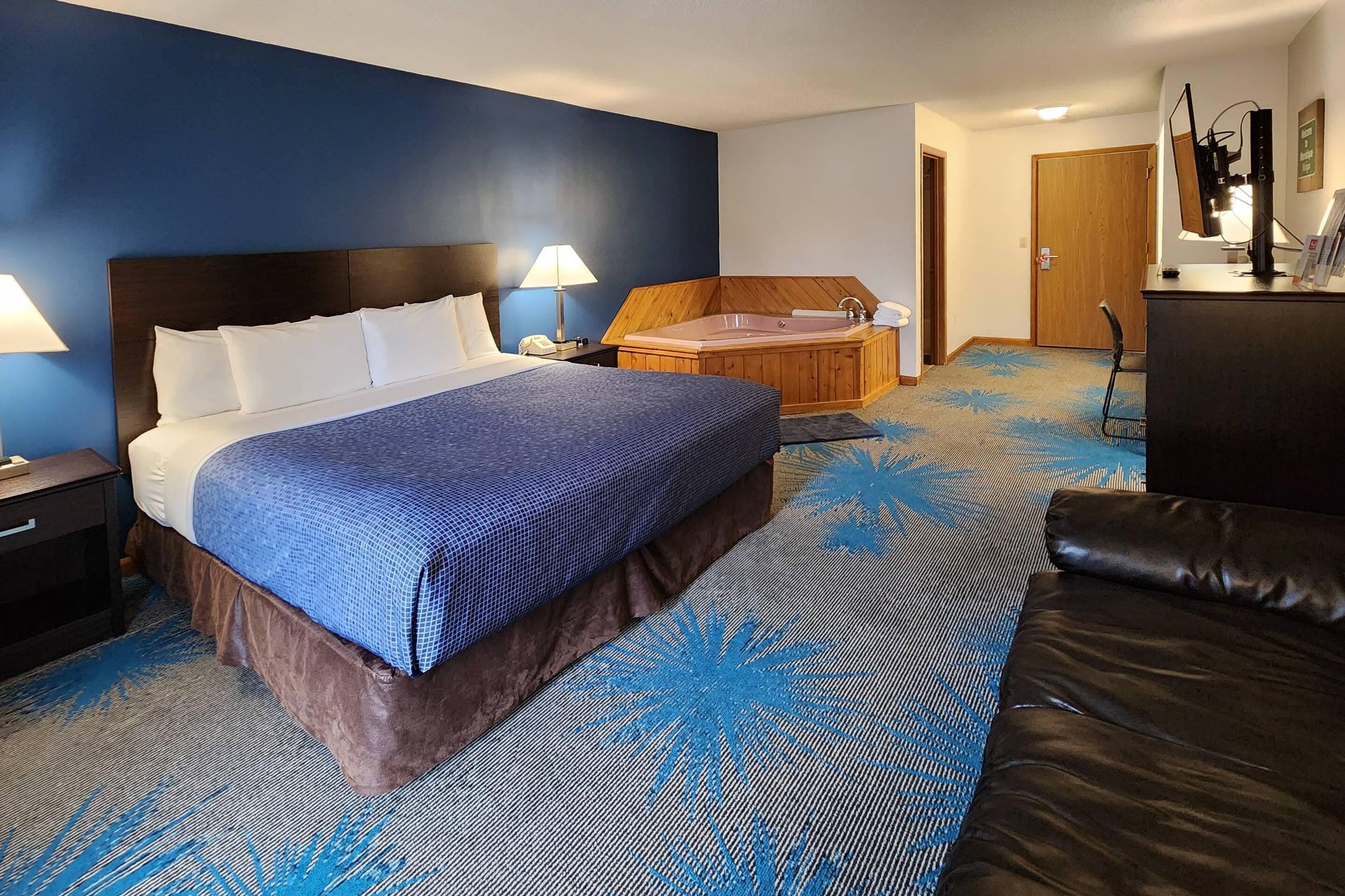 A hotel room with a bed, a bathtub, a desk, and a chair.