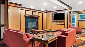 Ein Hotelzimmer mit rotem Sofa, einem Glastisch, einem Flachbildfernseher und einem Kamin.