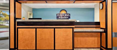 Zona de recepción con el letrero de Days Inn, un mostrador de recepción y un reloj en la pared.