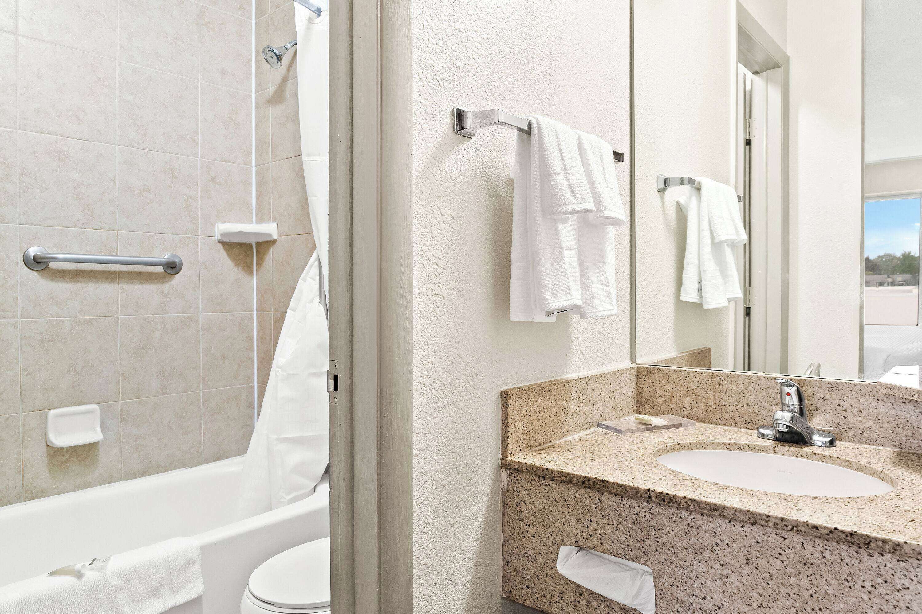 A bathroom with a bathtub, toilet, sink, and a mirror.