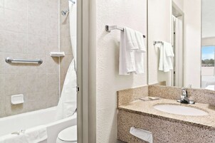 Un baño con bañera, inodoro, lavabo y espejo.