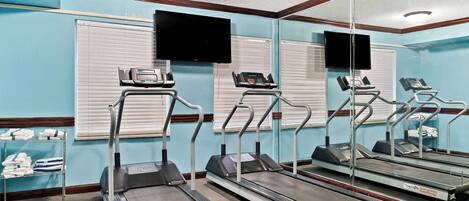 A fitness room with treadmills, a TV, and a mirror.