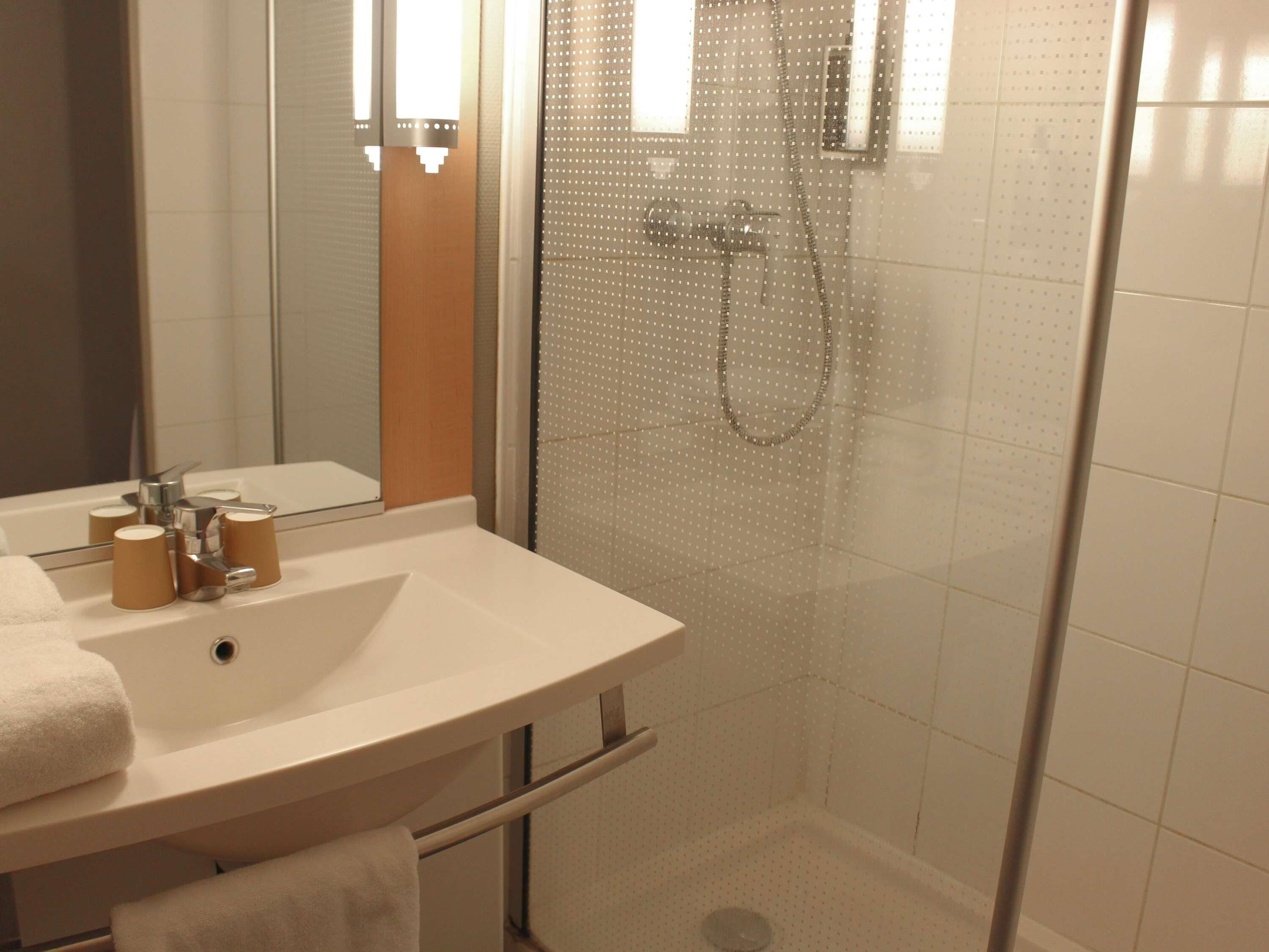 A bathroom with a sink, mirror, and shower.