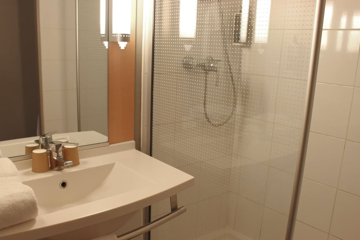 A bathroom with a sink, mirror, and shower.