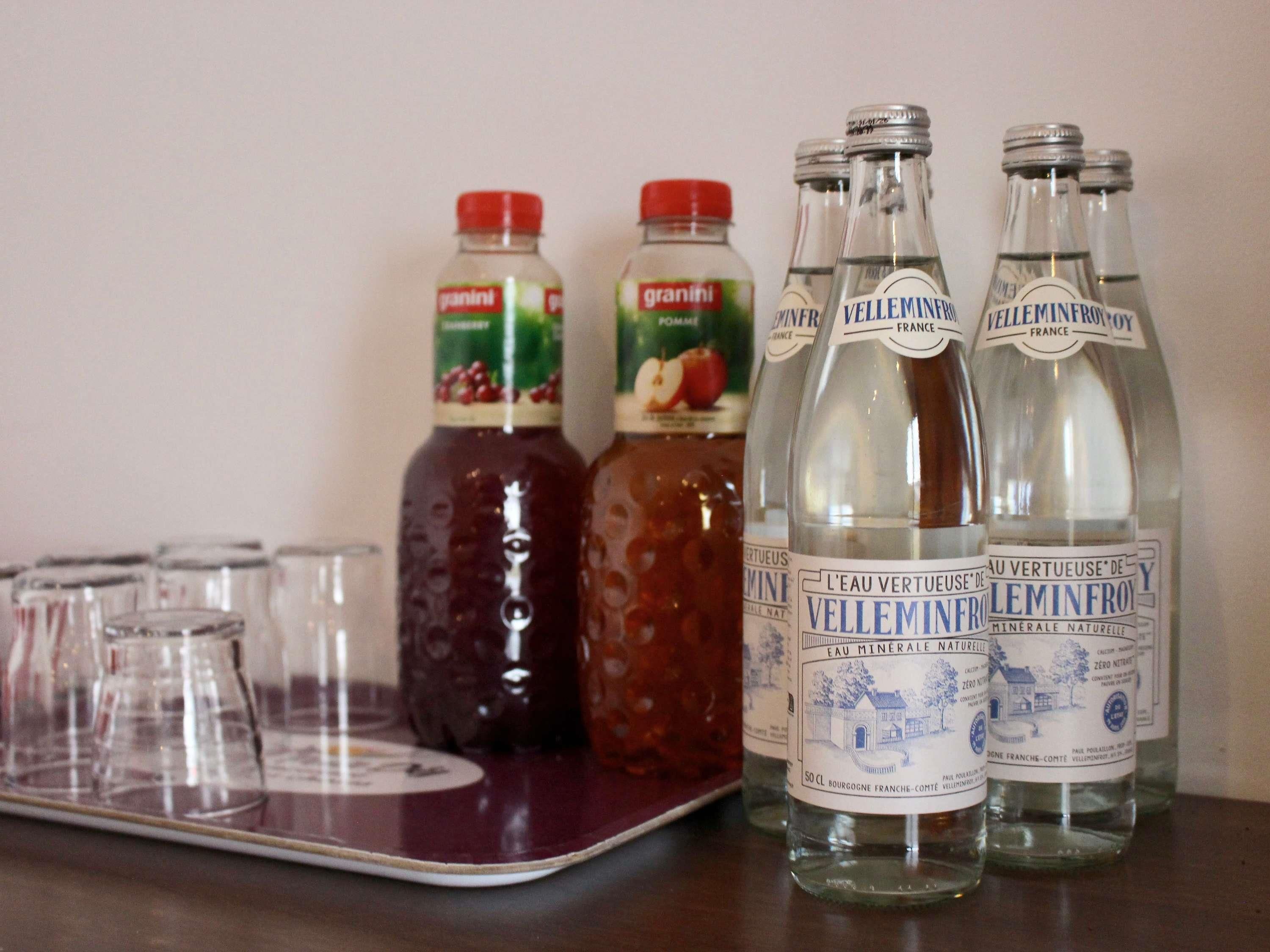 A table with bottles of granini and Velleminfroy mineral water, and empty glasses.