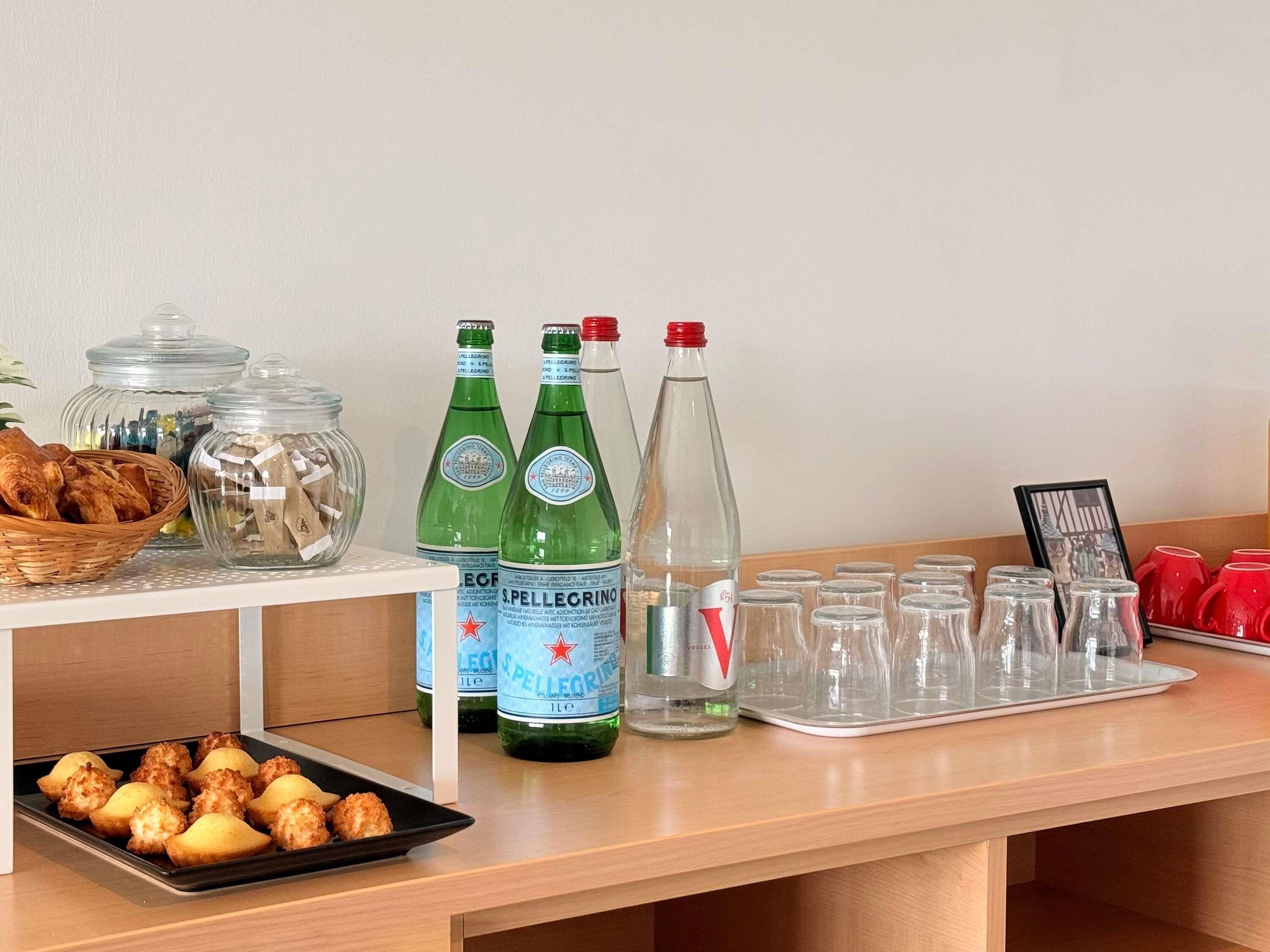 Una mesa de buffet con comida, botellas y vasos.