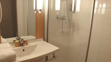 Un baño con lavamanos blanco, espejo y ducha.