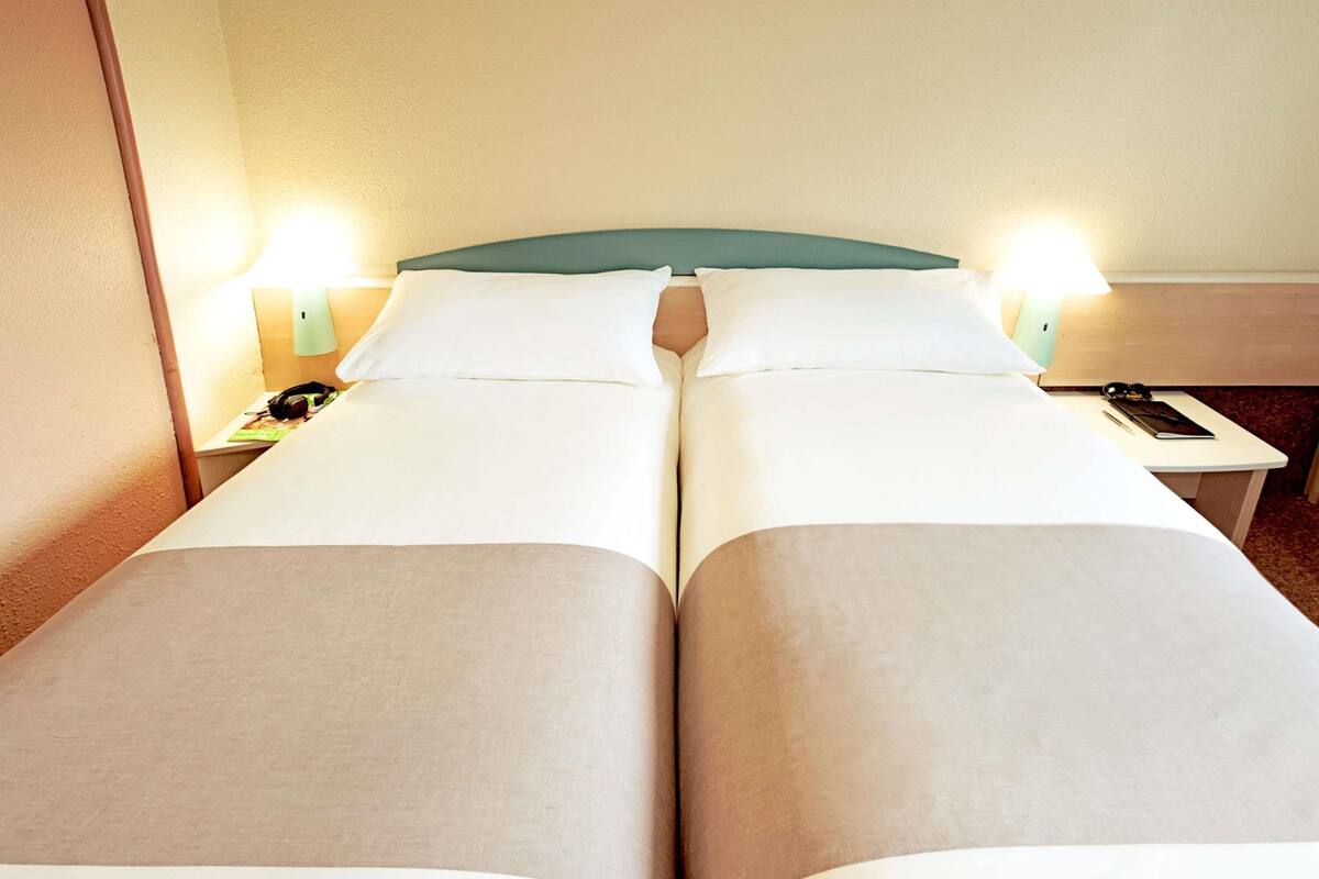 Una cama doble con dos mesitas de noche, cada una con una lámpara y un teléfono.