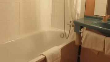Een badkamer met een bad, een douche en een wastafel met een handdoekhouder.