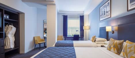 Une chambre d’hôtel avec deux lits, un coin salon, une armoire et une fenêtre avec des rideaux.
