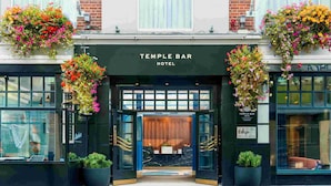 The entrance of Temple Bar Hotel with a black facade, large glass windows, and hanging flower baskets.