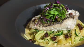 A dish with fish, greens, and pasta.