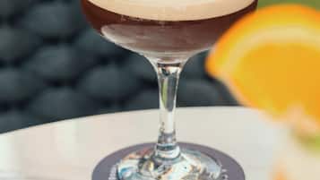 A cocktail in a martini glass on a table with a coaster.