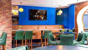 Un interior de restaurante con paredes de ladrillo, sillas tapizadas de verde y paredes azules.