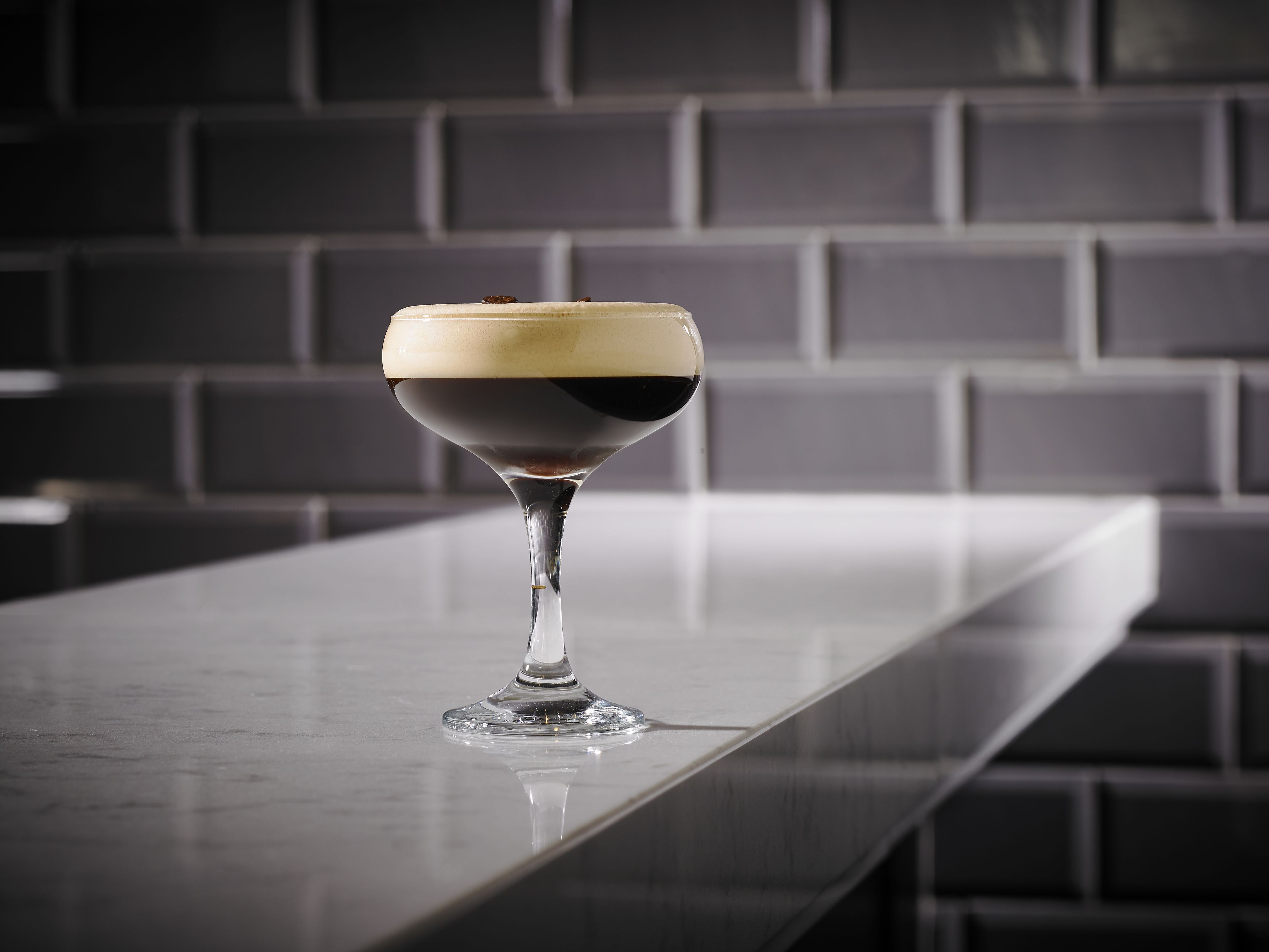 Una copa de martini con una bebida en capas sobre una barra.