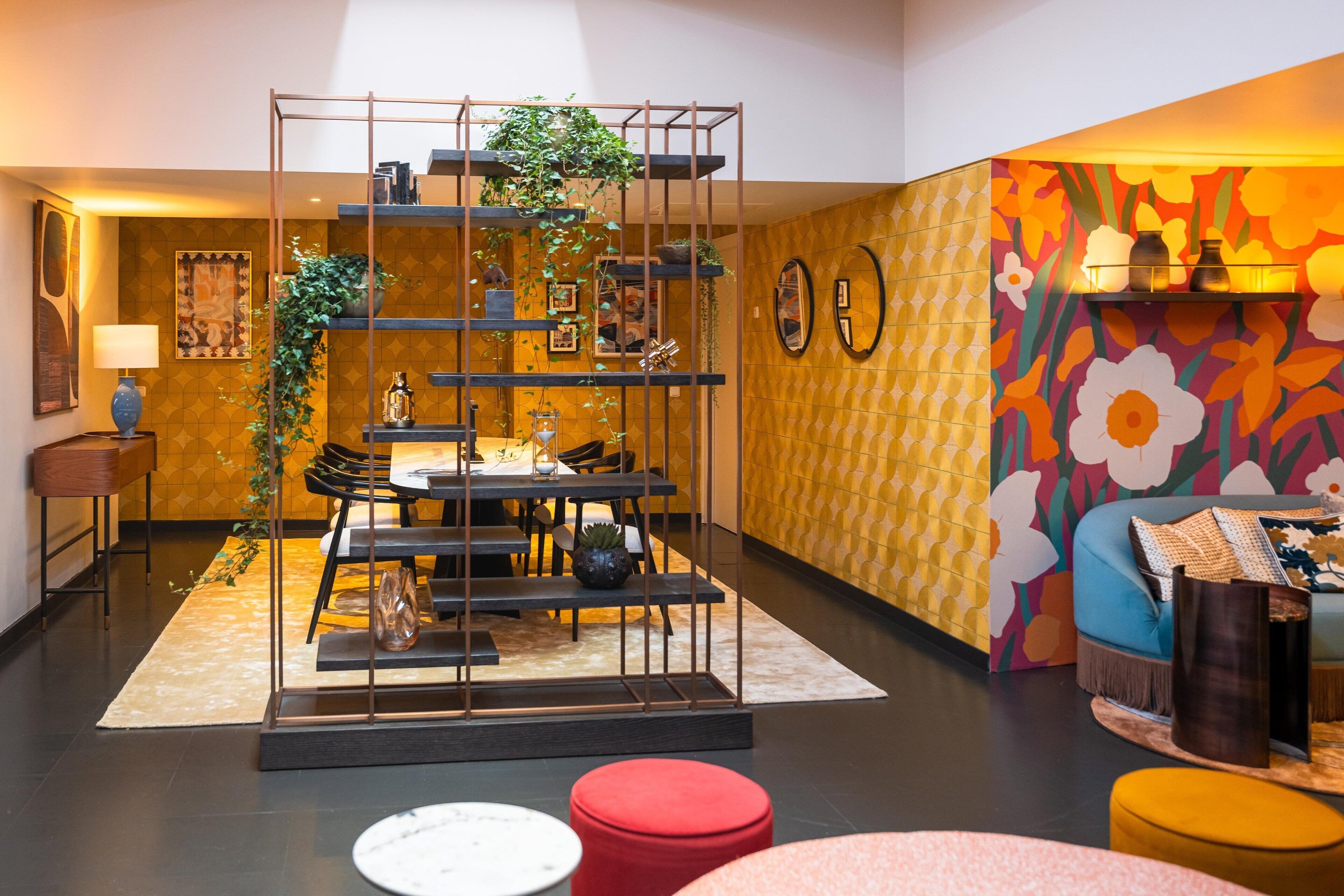 A modern interior with a dining area, a sofa, and a vibrant floral wall.