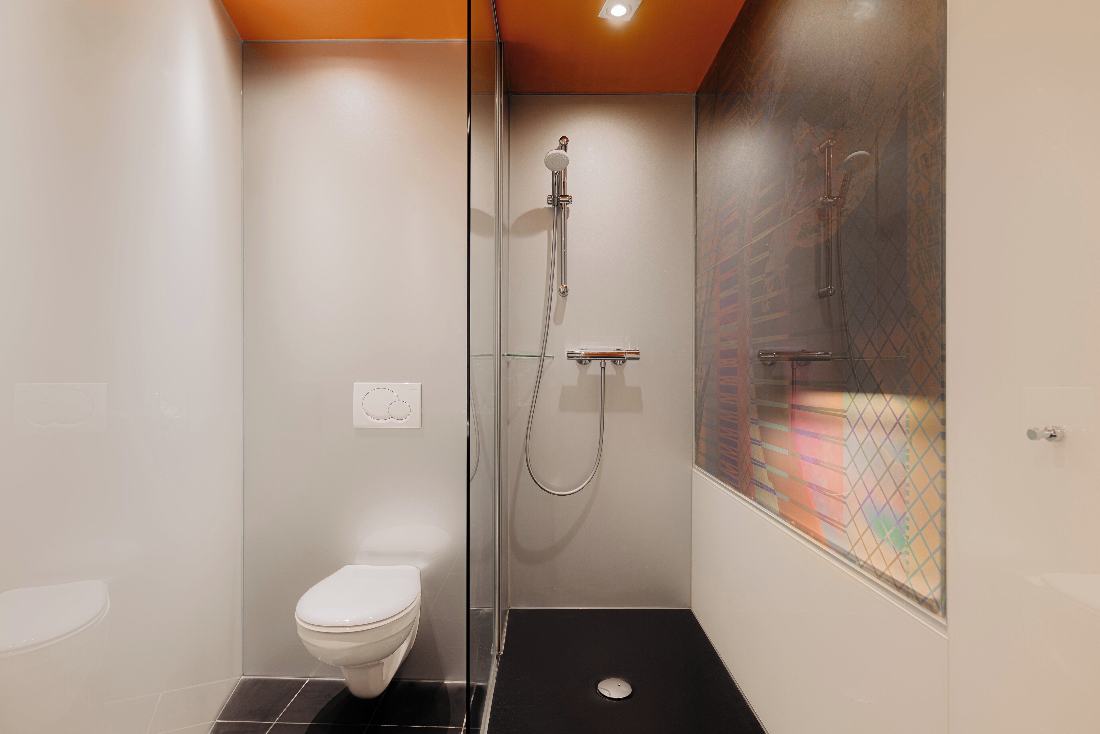 A modern bathroom with a glass-enclosed shower, a white toilet, and a black floor.