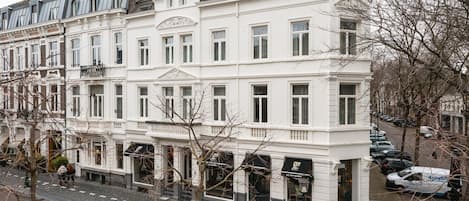 Un edificio blanco de varios pisos con amplios ventanales y un estilo arquitectónico clásico.