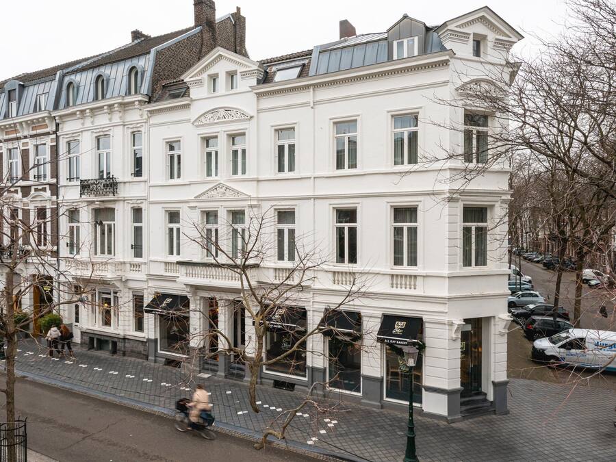 A multi-story white building with large windows and a classic architectural style.