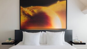 A neatly made bed with white bedding, a black headboard, and two bedside tables with a green mug and a bottle on one. - Leonardo Boutique Hotel Maastricht City Center (Maastricht)