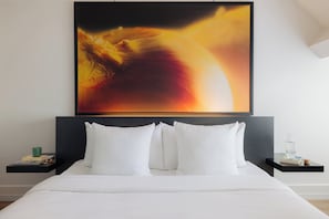 A neatly made bed with white bedding, a black headboard, and two bedside tables with a green mug and a bottle on one. - Leonardo Boutique Hotel Maastricht City Center (Maastricht)