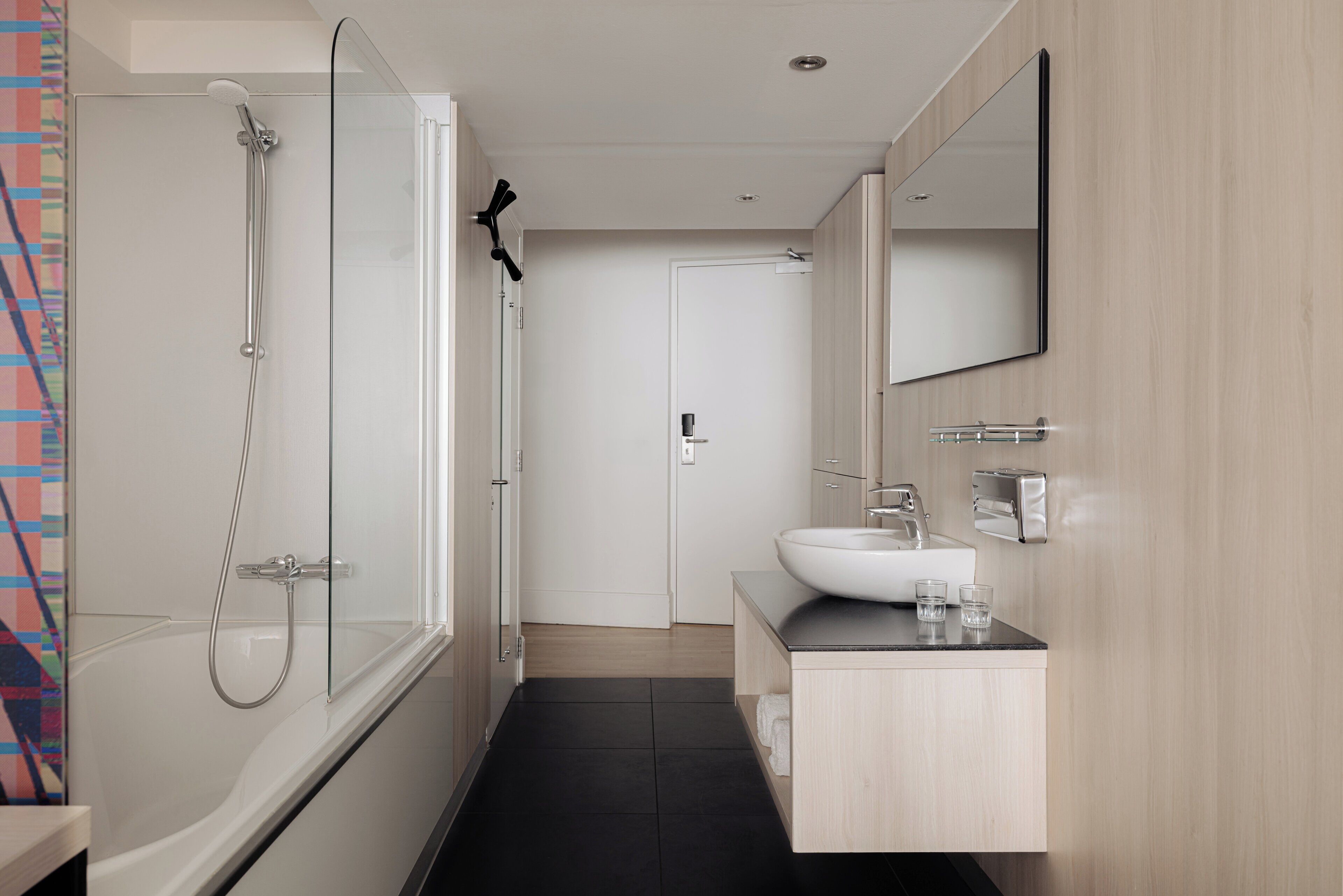 Un bagno moderno con doccia vetrata, lavabo bianco e specchio sopra il lavabo.