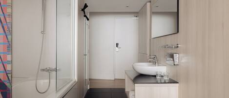 A modern bathroom with a glass-enclosed shower, a white sink, and a mirror above the sink.