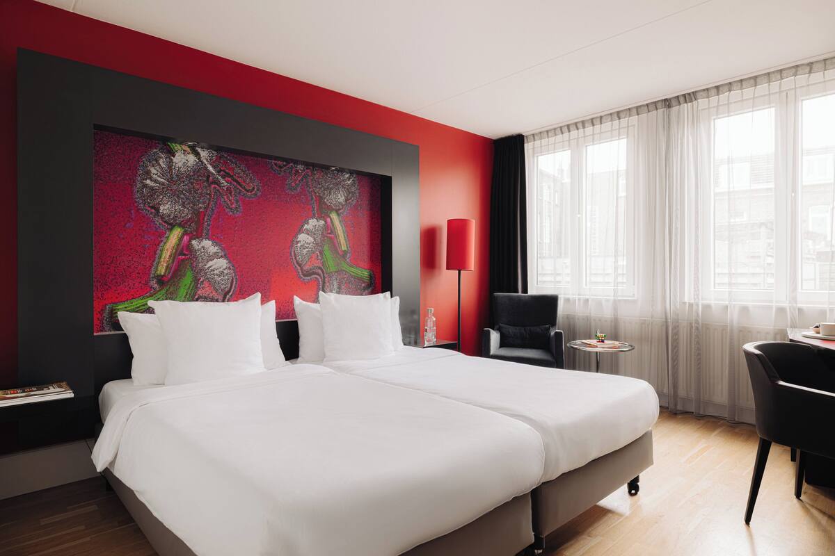 A modern hotel room with a large bed, a desk, and a chair.